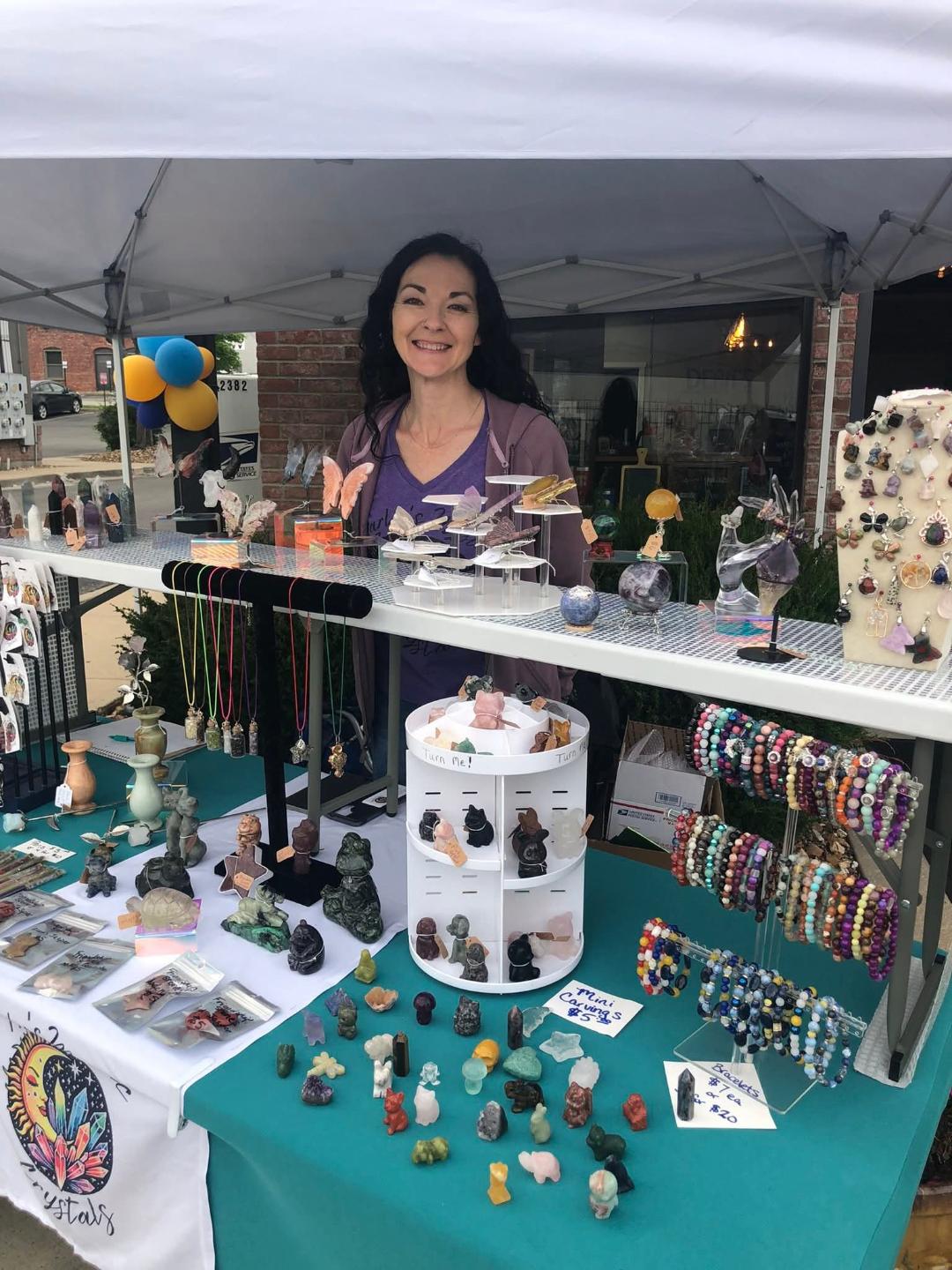 Tracy at a vendor table showing off handmade crystal items